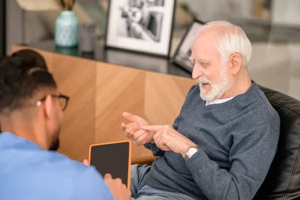 Pensionista concentrado enumerando algo en conversación con su cuidador — Foto de Stock