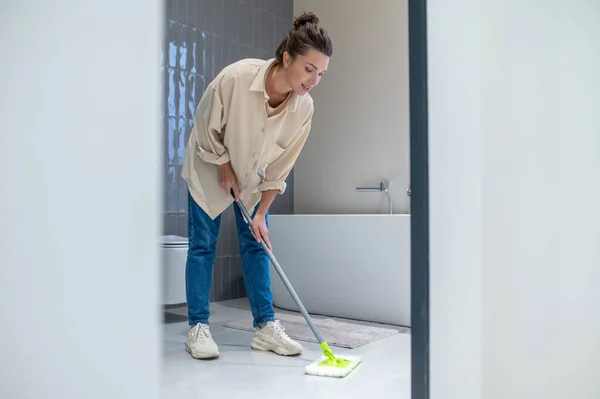 Νεαρή γυναίκα καθαρίζει το πάτωμα στο σπίτι — Φωτογραφία Αρχείου