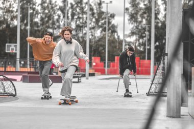 Happy young people riding skateboards in park