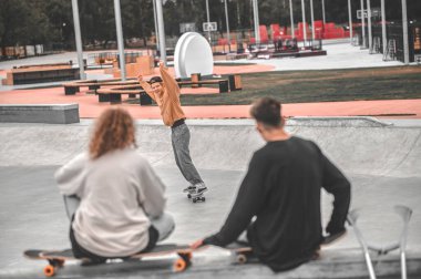 Guy sliding on skateboard and friends with back