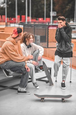 Girl and two guys are cheerful talking outdoors
