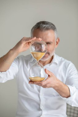 Kum saati tutan adam yüz hizasında