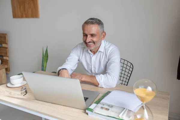 Man talking on video call smiling into laptop — стоковое фото