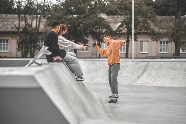 Guy smiling on skateboard and friends watching — Zdjęcie stockowe