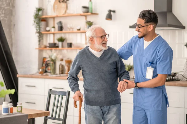 Medical worker helping his patient to move around the apartment — Stock Photo, Image