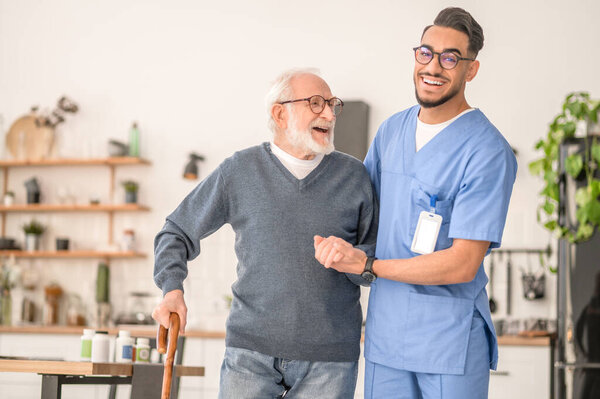 Nurse helping his senior patient to walk with a cane
