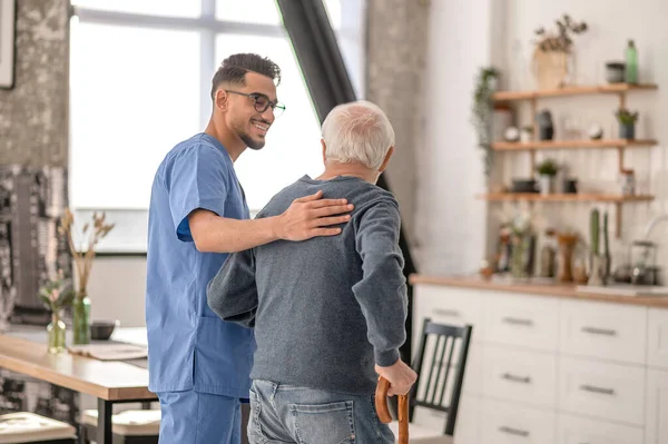 Nurse helping his patient to walk with a walking stick — Stockfoto