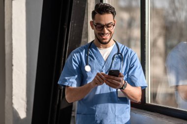 Memnun doktor cep telefonuyla birine mesaj atıyor.