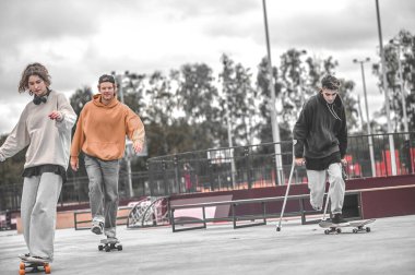 Koltuk değnekli bir adam ve kaykay süren bir kız.