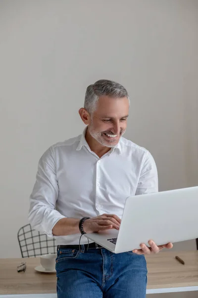 Good-looking gray-haired man working on laptop — Photo