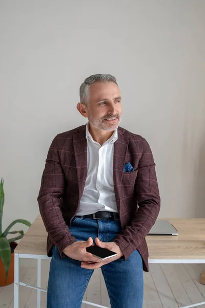 Een man in een bruin jasje staat bij de tafel en ziet er attent uit — Stockfoto