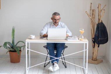 Man with glasses looking intently at laptop in office