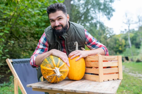 Een donkerharige jonge boer met pompoenen die er tevreden uitziet — Stockfoto