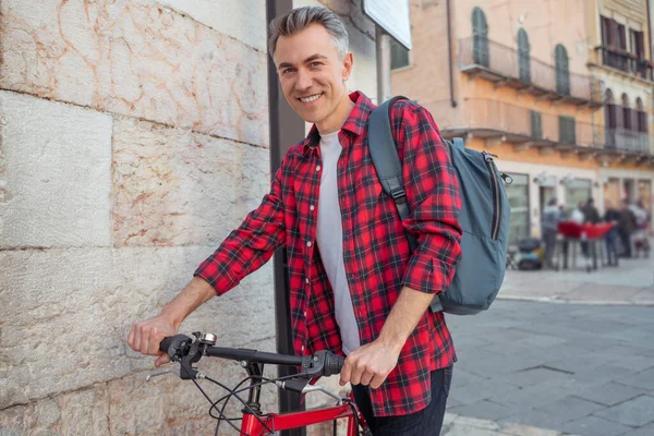 Mężczyzna z rowerem patrzący w kamerę na ulicy — Zdjęcie stockowe