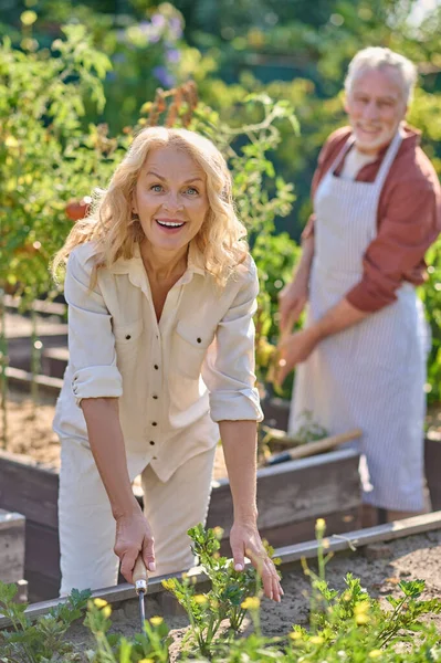 Woman smiling at camera working near vegetable garden — Stock fotografie
