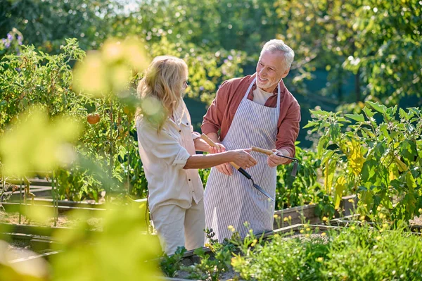 Man en vrouw met tuingereedschap in de tuin — Stockfoto