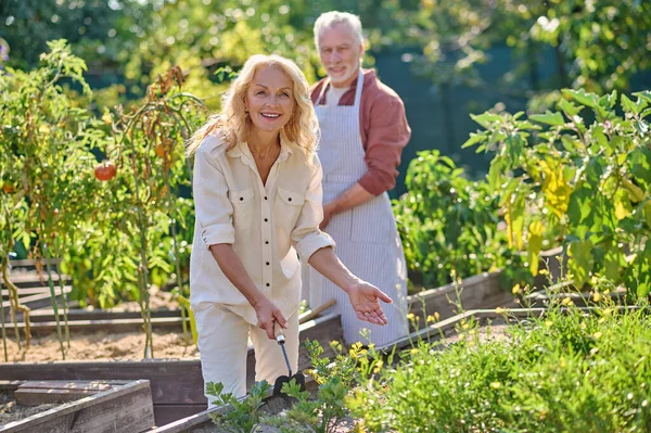 Joyful woman pointing to garden and man behind — Stockfoto