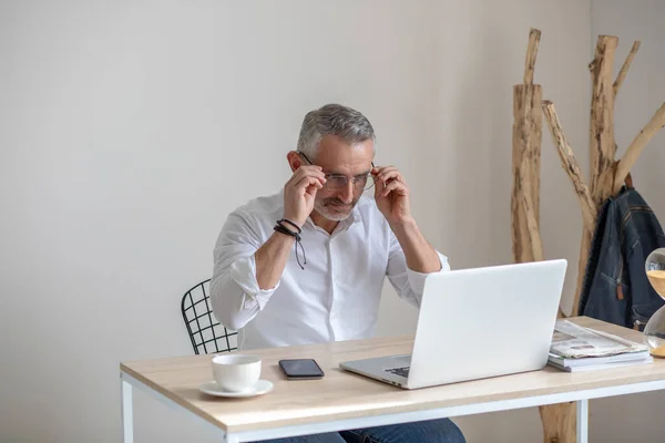 Man putting on glasses looking at laptop screen — Foto de Stock