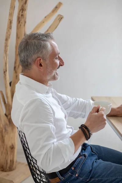 Man met koffie zit zijwaarts naar de camera — Stockfoto