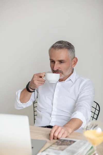 Confident god-looking businessman having morning coffee in the office — стоковое фото