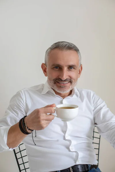 Confident god-looking businessman having morning coffee in the office — Stockfoto