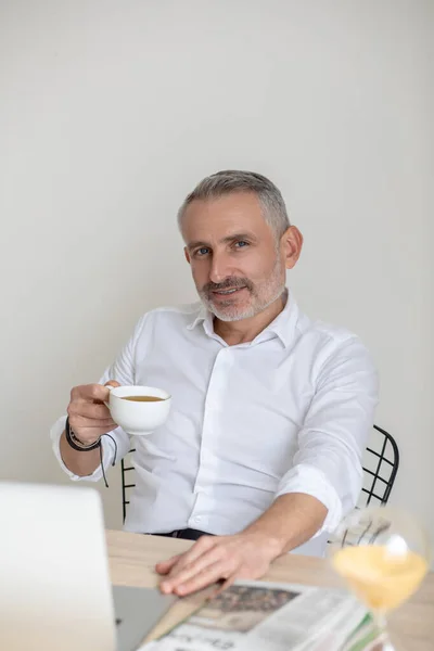 Confident god-looking businessman having morning coffee in the office