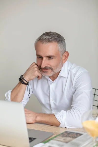 Mężczyzna w białej koszuli i okularach pracujący w biurze i wyglądający na zaangażowanego. — Zdjęcie stockowe