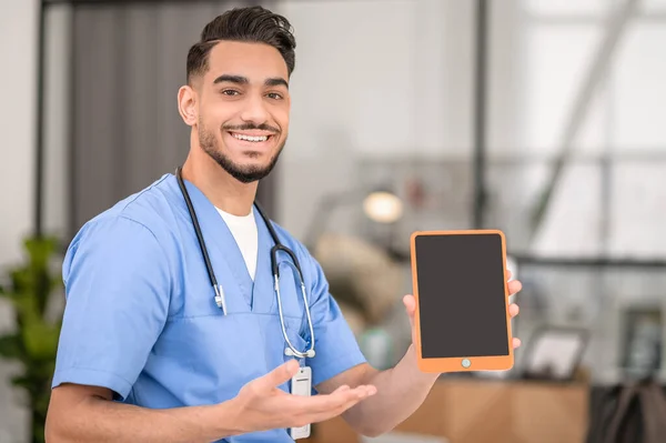 Jovem médico feliz mostrando seu tablet — Fotografia de Stock