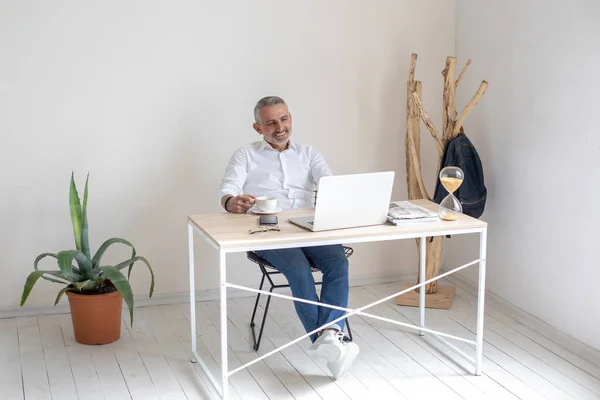 Homem sentado com café sorrindo na tela do laptop — Fotografia de Stock