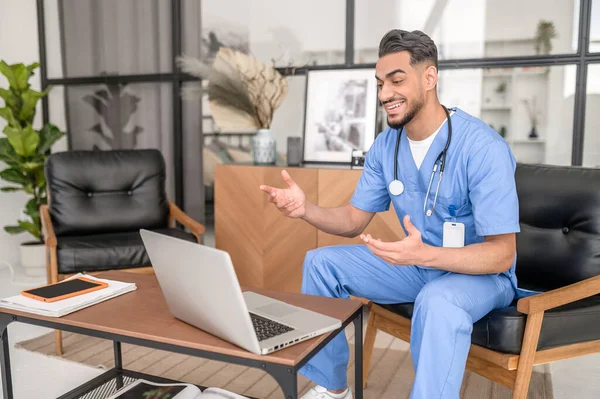 Joven médico alegre consultando a su paciente en línea — Foto de Stock