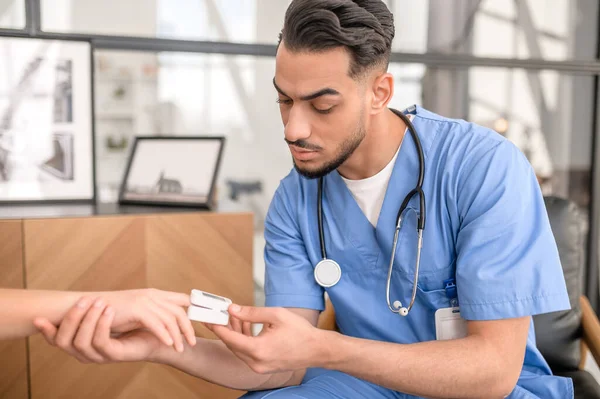 Concentrated physician placing a pulse oximeter on a person fingertip — Stock Photo, Image