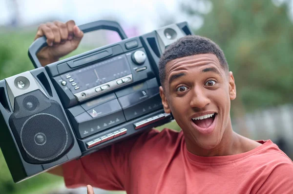Guy with record-player on shoulder enthusiastically looking at camera — Stock Photo, Image