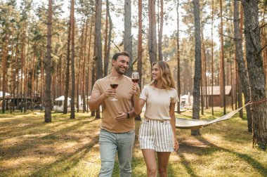 Aşık bir adam gülümseyen, güzel bayan arkadaşına bir kadeh şarap kaldırıyor.