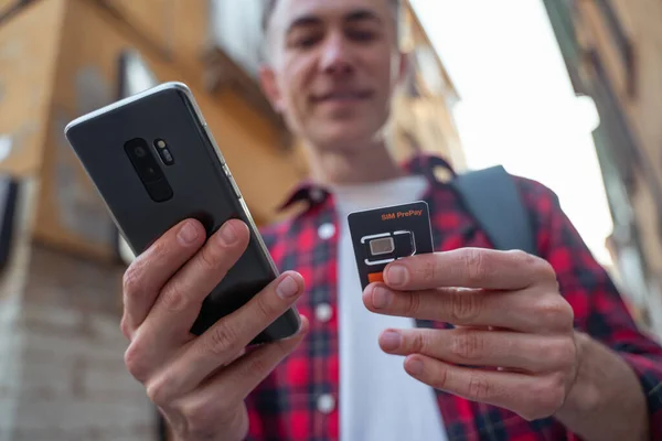 Using the gadget. Man in red plaid shirt with a gadget in hands