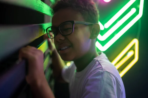 不思議な十代の男の子で眼鏡をかけてギャップを通って見る木のスラットの壁 — ストック写真