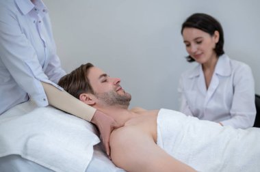 Masaj. Genç bir adam spa salonunda boyun ve omuz masajı yaptırıyor.