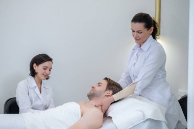 Masaj. Genç bir adam spa salonunda boyun ve omuz masajı yaptırıyor.