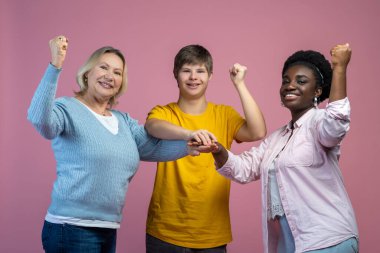 Team. Guy with down syndrome and two women standing touching with palms smiling at camera with raised fists clipart