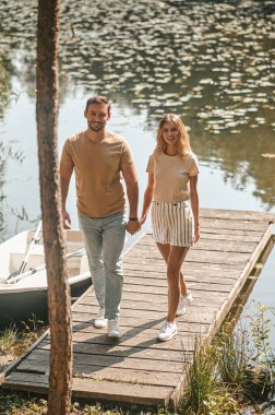 Gülümseyen mutlu romantik genç adam, güzel bayan arkadaşını iniş sahnesinde elinden tutuyor.