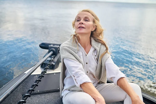 乘船旅行 一个金发碧眼的成熟女人 身穿白衣 坐在船上 看起来像在做梦 — 图库照片