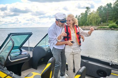 Can yeleği. Sarışın bir kadının can yeleğini giymesine yardım eden bir adam.