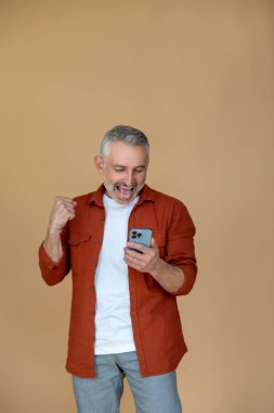 Heyecan. Akıllı telefonu olan ve heyecanlı görünen bir adam.