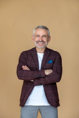 Keyfin yerinde. Kollarını kavuşturmuş, mutlu ve gülümseyen bir adam.