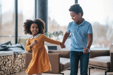 Dans eden çocuklar. Bir kız ve bir erkek dans ediyor ve neşeli görünüyorlar.