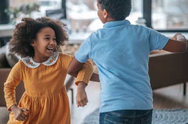 Dans eden çocuklar. Bir kız ve bir erkek dans ediyor ve neşeli görünüyorlar.