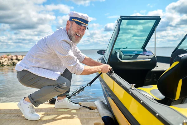 Ready to sail. A man in a captains cap getting the boat ready