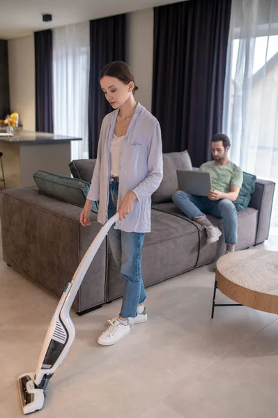 Thuis Leven Jonge Volwassen Vrouw Stofzuigen Vloer Bebaarde Man Zoek — Stockfoto