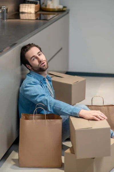 Fatiga Hombre Barbudo Joven Mirando Cámara Sentada Suelo Cerca Cajas — Foto de Stock