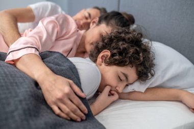 Birlikte uyukluyorlar. Sevimli bir aile aynı yatakta yatıyor.