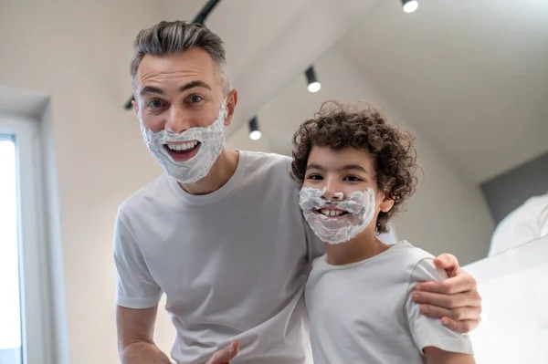 有趣的剃须 爸爸和儿子满脸都是泡沫 看起来很滑稽 — 图库照片
